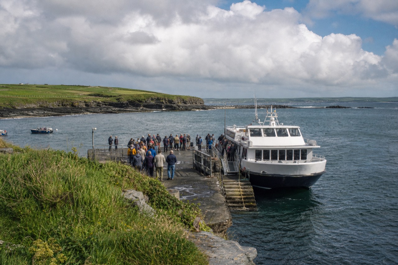 Doolin Pier on a busy summer afternoon, a small cliff-cruise boat loading passengers at the quay with the grey Atlantic and low green Clare coast behind.